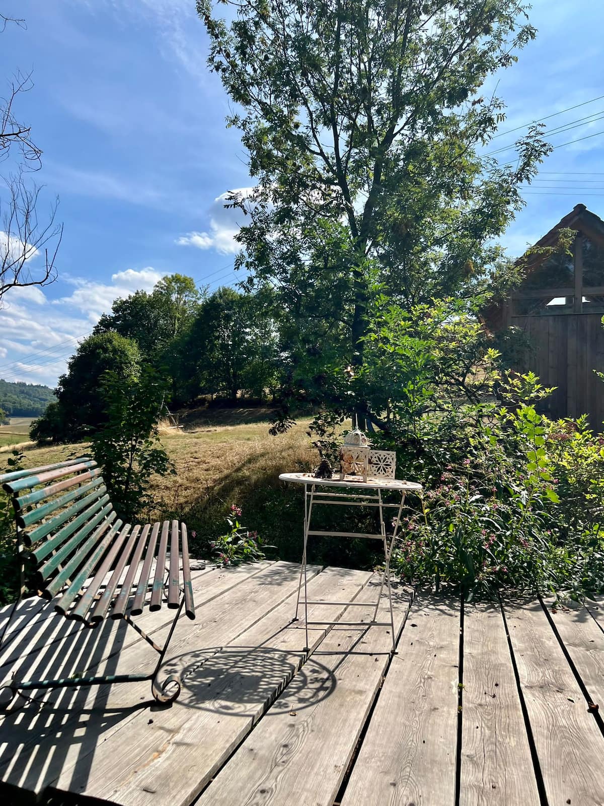 Holzterrasse mit Liegestuhl im Garten des Gesäßhofs