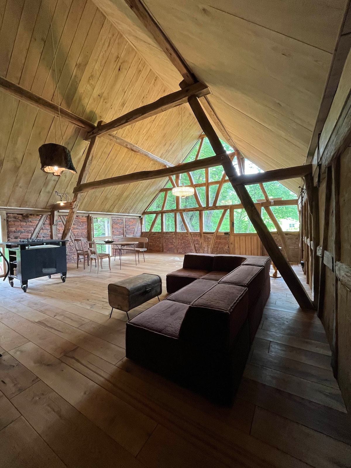 Wohnbereich im Loft mit Sofa unter offenem Dachstuhl und Glasgiebel am Gesäßhof