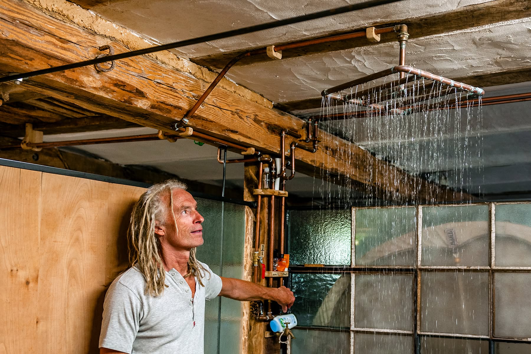 Selbstgebaute Regendusche aus Kupferrohren unter alten Holzbalken am Gesäßhof