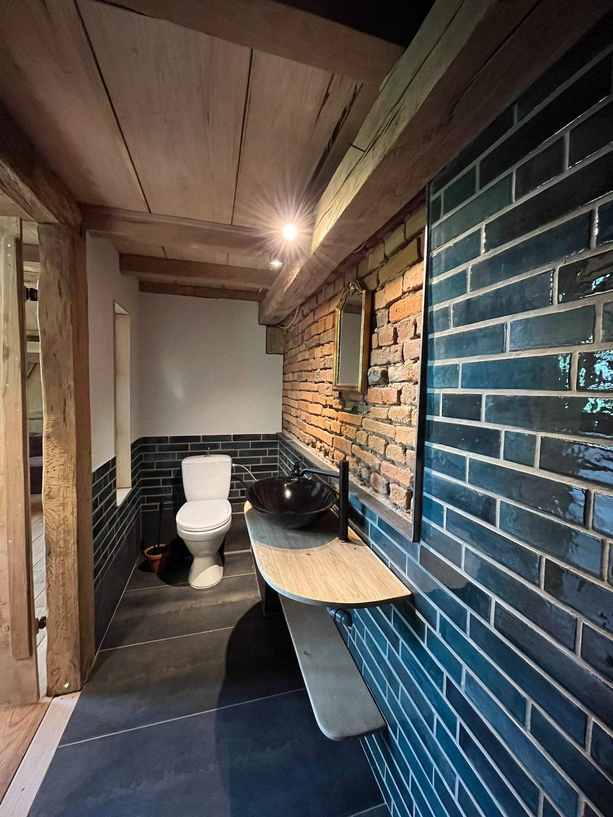Badezimmer im Loft des Gesäßhofs mit blauen Fliesen und Ziegelwand